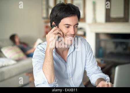 Man talking on cell phone while using laptop computer Stock Photo