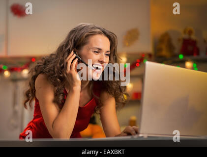 Happy young woman having video chat on laptop in christmas decorated kitchen Stock Photo