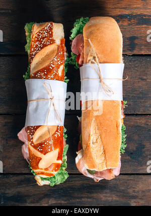 Submarine sandwiches with vegetables and prosciutto on wooden background with blank space Stock Photo