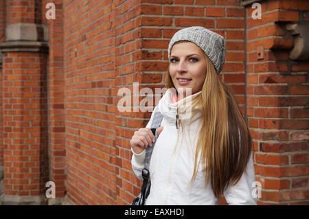 outdoor portrait of a young woman wearing woolen hat in front of red brick building Stock Photo