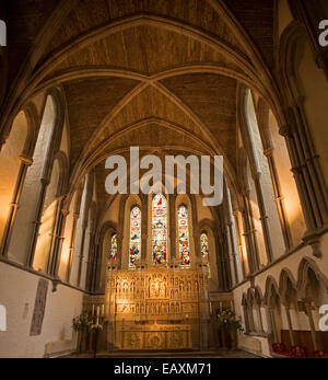 Interior of 11th century Brecon cathedral showing high nave with vaulted ceiling, stained glass windows & carved reredos, Wales Stock Photo