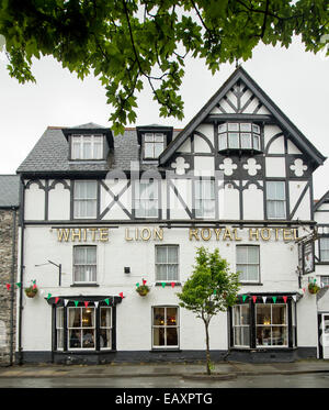 18th century White Lion Royal Hotel with ornate black and white Tudor style facade and overhanging trees in Welsh town of Bala Stock Photo