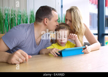 Parents kissing son playing on pad Stock Photo