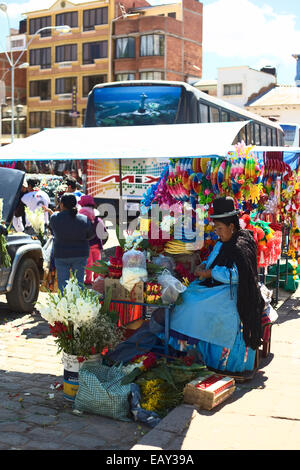 Woman dressed in traditional clothes selling ornaments for the blessing of the cars in Copacabana, Bolivia Stock Photo