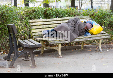 Sofia, Bulgaria - November 4, 2014: Homeless man is sleeping on a bench in the center of Sofia. Years after joining the EU Bulga Stock Photo