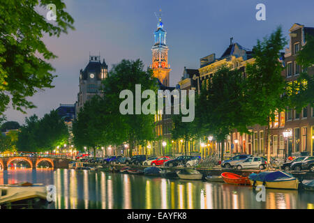 Night city view of Amsterdam canal and Westerkerk church, boats and bridge, Holland, Netherlands. Toning. Stock Photo