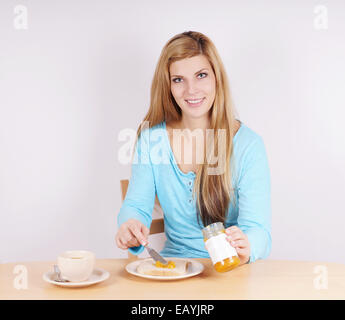 young woman spreading marmelade on her toast at the breakfast table Stock Photo