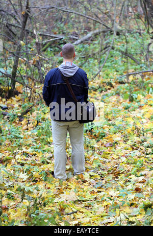 A man stands in the forest on green leaves Stock Photo