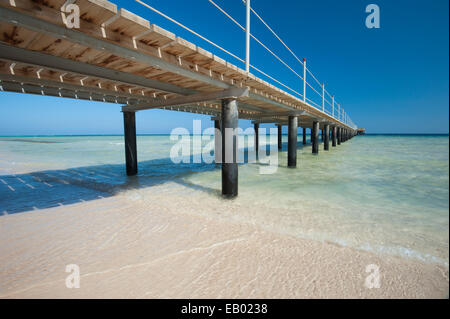 Wooden jetty structure going out to sea on tropical beach resort Stock Photo