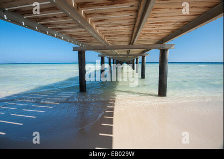 Wooden jetty structure going out to sea on tropical beach resort Stock Photo