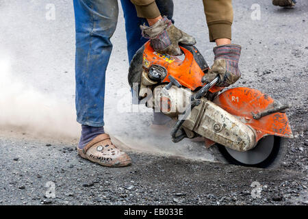 A man works cut asphalt road with a diamond cutter, No protective work gear, Czech Republic Stock Photo