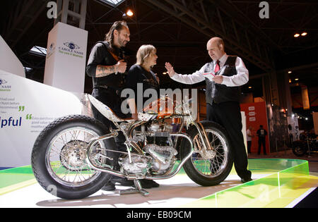 Motorcycle Live, The NEC, Birmingham, England, UK. 22nd November 2014. Today is the feast day of St Columbanus (23rd November).  St Columbanus is the patron saint of motorcyclists and the Reverend Paul Sinclair was on hand this weekend at the Motorcycle Live show in Birmingham to bless the gathered bikes and bikers. He is pictured giving a blessing to Vic and Lin Jefford and their unique hand built bike. Credit:  Simon Hadley /Alamy Live News Stock Photo