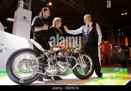 Motorcycle Live, The NEC, Birmingham, England, UK. 22nd November 2014. Today is the feast day of St Columbanus (23rd November).  St Columbanus is the patron saint of motorcyclists and the Reverend Paul Sinclair was on hand this weekend at the Motorcycle Live show in Birmingham to bless the gathered bikes and bikers. He is pictured giving a blessing to Vic and Lin Jefford and their unique hand built bike. Credit:  Simon Hadley /Alamy Live News Stock Photo