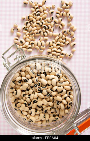 Black Eyed Peas in a glass storage jar on a pink check table cloth Stock Photo