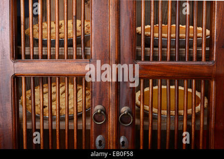 Closeup of an old fashioned pie safe with pumpkin and apple pies behind the doors. Four fresh baked holiday pies on two shelves Stock Photo