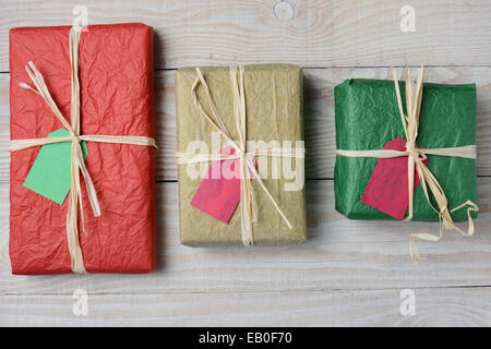 High angle image of three tissue paper wrapped Christmas presents. Horizontal format on a whitewashed rustic wood table. Stock Photo