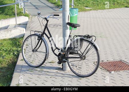 A bicycle parked tied to the stake, in Italian city. Stock Photo