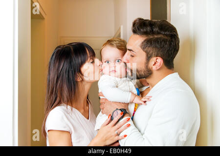 Mother and father kissing their baby Stock Photo