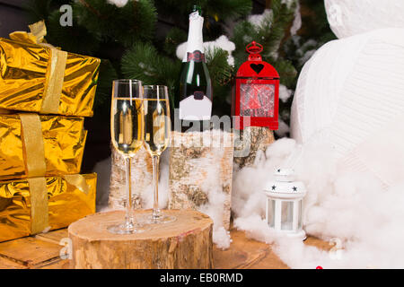 Christmas celebration with champagne in stylish glass flutes with luxury gold gifts, a festive lantern and a snowman Stock Photo