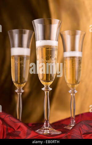 Champagne flutes against an abstract gold background. Stock Photo