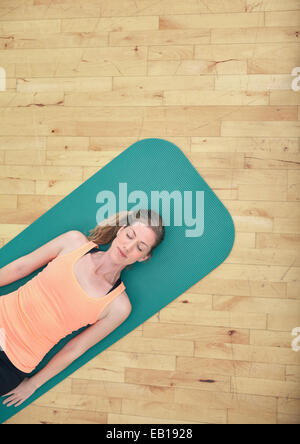 Top view of woman relaxing on yoga mat with copy space. Fitness female lying on exercise mat at gym. Stock Photo