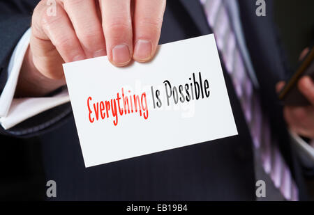 A businessman holding a business card with the words,  Everything Is Possible, written on it. Stock Photo