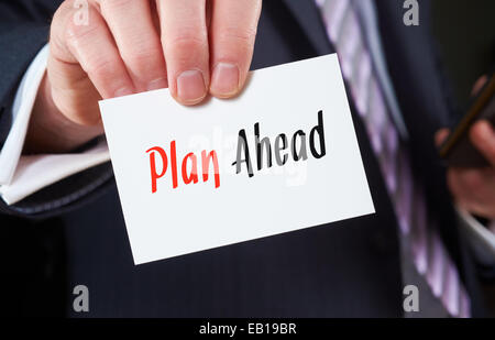 A businessman holding a business card with the words, Plan Ahead, written on it. Stock Photo