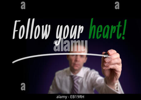 A businessman writing Follow Your Heart on a screen. Business Concept. Stock Photo