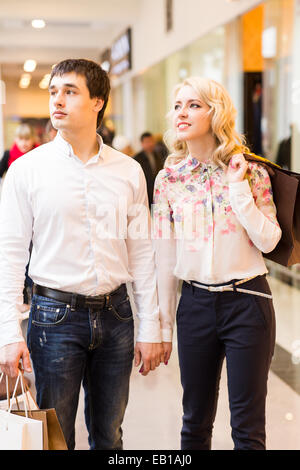 Happy young couple walking in the mall carrying shopping bags Stock Photo