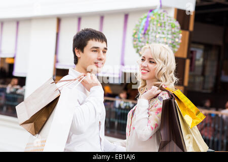 Happy young couple walking in the mall carrying shopping bags Stock Photo