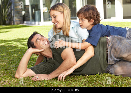 Happy family with son laying in the garden in front of a house Stock Photo