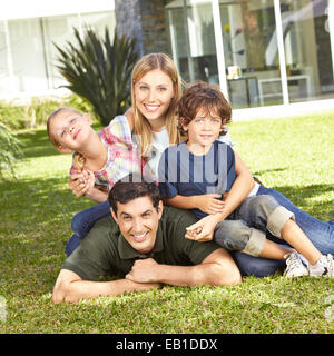 Happy family with daughter and son laying in a garden in front of house Stock Photo