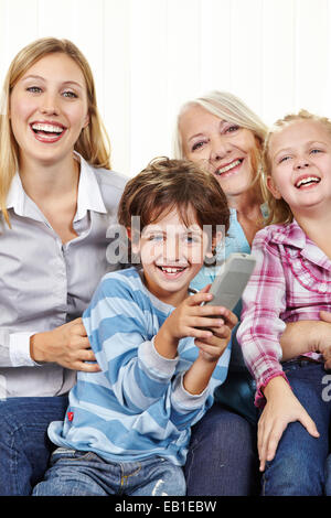 Happy family with remote control watching TV in living room Stock Photo