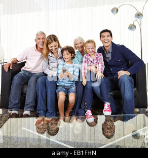 Happy big family on sofa watching Smart TV with remote control Stock Photo