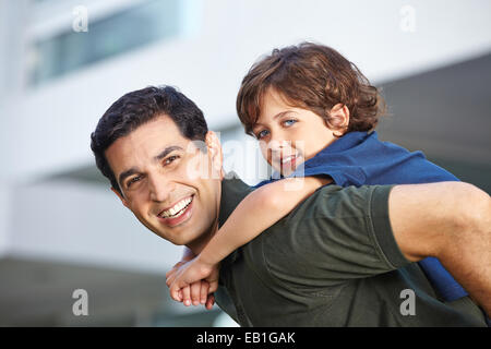 Happy child riding piggyback on his smiling father Stock Photo