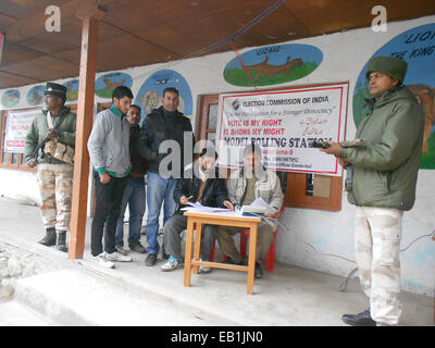 Srinagar, Kashmir. 24th November, 2014. Goverrnment employee cheks electronic voting machine (EVM) as Indian paramilitary troopers stand guard out side polling both at ganderbal district some 20 kms from here secuirty beefed up on the first phase Assembly Elections on tomorrow 25th November. Credit:  sofi suhail/Alamy Live News Stock Photo