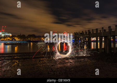 Light painting, spinning lit steel wool on a Thames beach at night Stock Photo