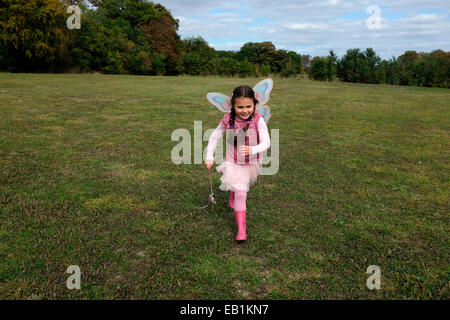 Young girl dressed as fairy running across a field Stock Photo