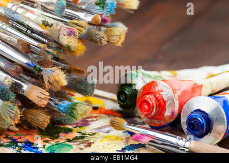 Artist paint brushes on wooden palette. Texture mixed oil paints