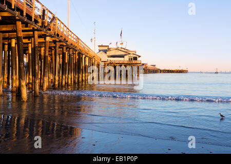 A low, setting sun casts a deep orange light on the pilings of the Santa Barbara pier, also know as Stearns Wharf. Stock Photo