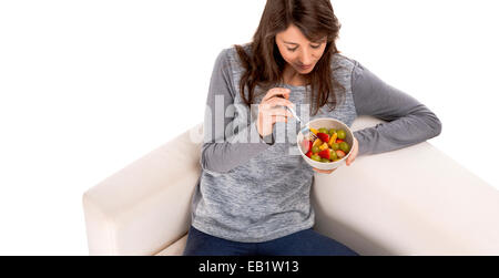 Beautiful woman relaxing on the sofa and eating a fruit salad Stock Photo