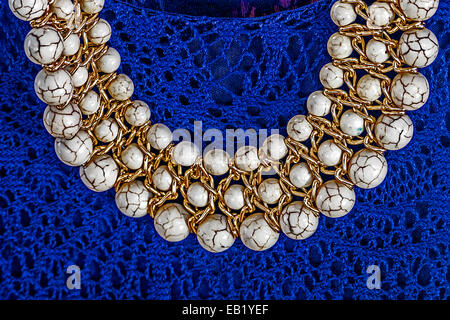 Old pearl necklace sitting on a background of blue embroidered dress. Stock Photo