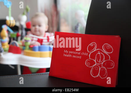 A red personal child health record book, issued to new children born in the UK and taken to each development appointment. Stock Photo