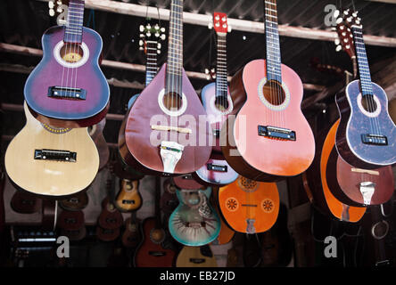 Beautiful hand crafted guitars hanging on display at a market stall in Serikin, Malaysian Borneo. Nice display of different designs and shaped guitars Stock Photo