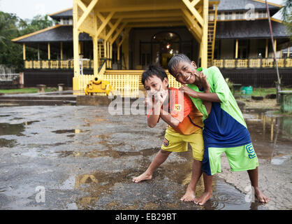 Candid portrait photograph of smiling Indonesian children having fun outside the Kraton (Royal Palace) of Pontianak in Indonesian Borneo Stock Photo