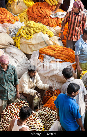 Hustle and bustle of activity at a market in India. The famous flower market at Howrah Bridge in Kolkata. Garlands of yellow orange flowers stacked Stock Photo