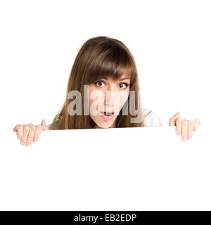 Young beautiful amazed woman holding blank white card. Stared excited girl with advertising empty board Stock Photo