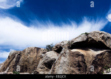 Wispy clouds crowning a rocky granite outcrop on the savannah known as a kopje. Stock Photo