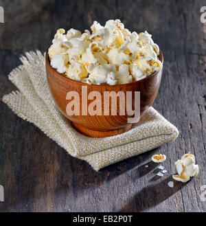 Fresh popcorn in bowl on old wooden table, isolated