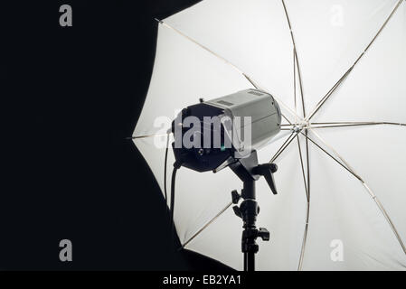 Photography Studio Flash Head with Umbrella and dark black copy space. Stock Photo